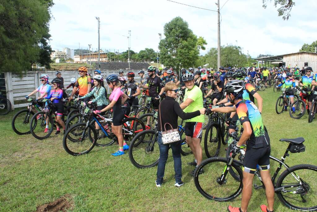 Grupo de ciclistas reunidos com suas bicicletas na área gramada durante a edição anterior do Pedal de Natal de São Marcos, que contou com grande participação de público.