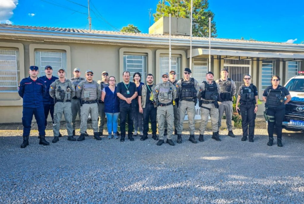 Efetivo da Brigada Militar e agentes de fiscalização reunidos em frente ao prédio institucional em São Marcos, com viaturas ao lado, durante a Operação Preservação.