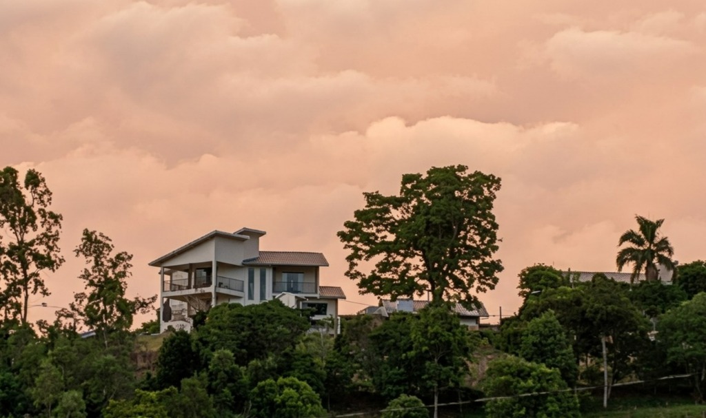 Céu com muitas nuvens e tonalidade alaranjada ao entardecer em área residencial de São Marcos, refletindo o calor e a nebulosidade desta terça-feira.