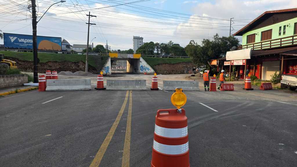 Bloqueio parcial na via sob o viaduto no bairro Nossa Senhora da Saúde, em Caxias do Sul, com cones, barreiras de concreto e trabalhadores sinalizando o trecho durante obras na ERS-122.