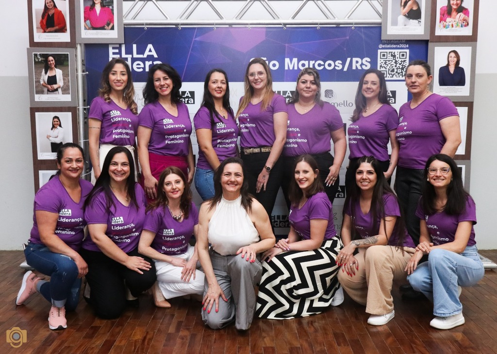 Grupo de mulheres participantes da edição anterior do ELLA Lidera, em São Marcos, posando para foto com camisetas roxas do projeto que incentivam a liderança e o protagonismo feminino.
